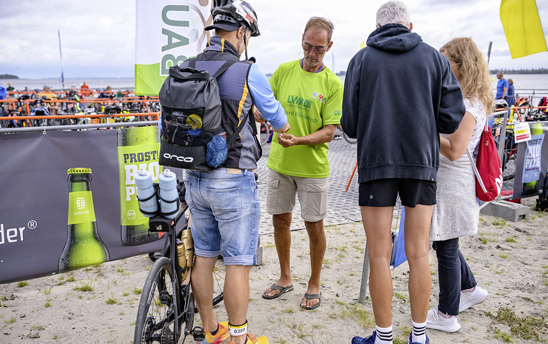 Ehrenamtliche Helfer bauen die Wechselzone für den Triathlon Stralsund auf, platzieren Fahrradständer in geraden Reihen.